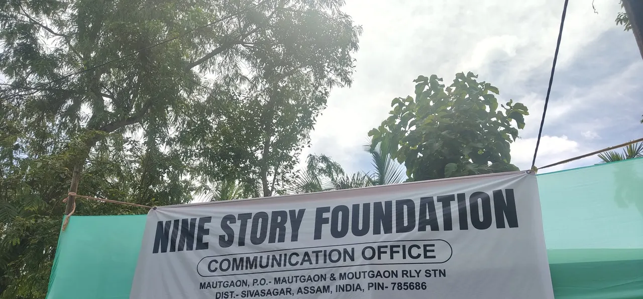 A Nine Story Foundation Communication Office banner strung between poles at the Mautgaon site
