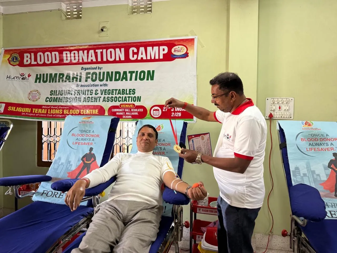 A Humrahi blood donation camp in Siliguri, a volunteer attending to a donor beneath the camp banner