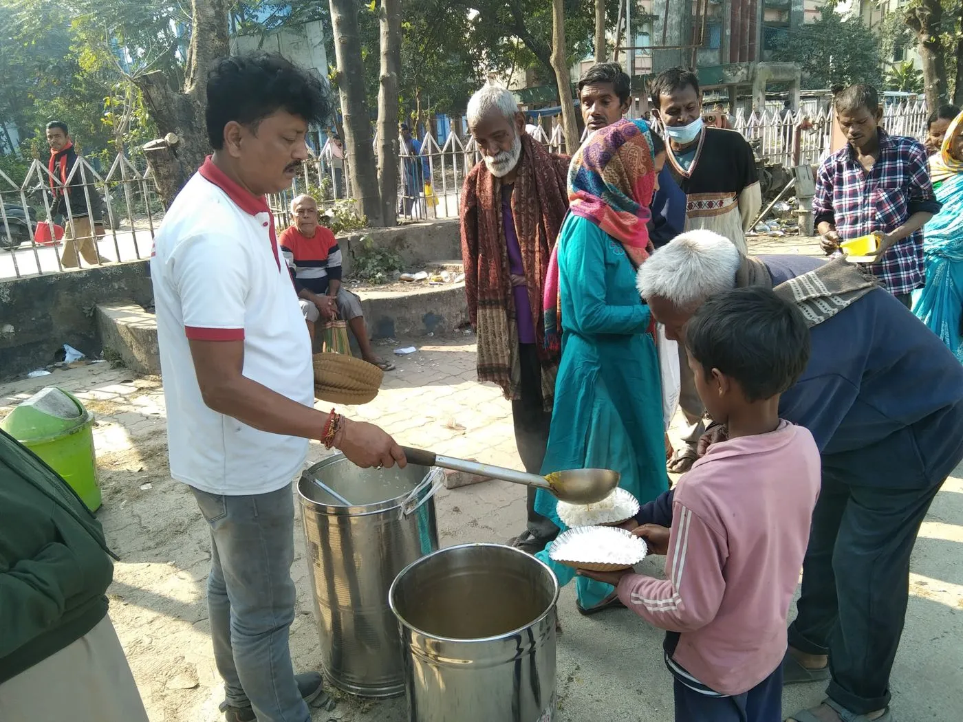 Humrahi volunteers serving warm meals from steel pots at a food distribution point in Siliguri