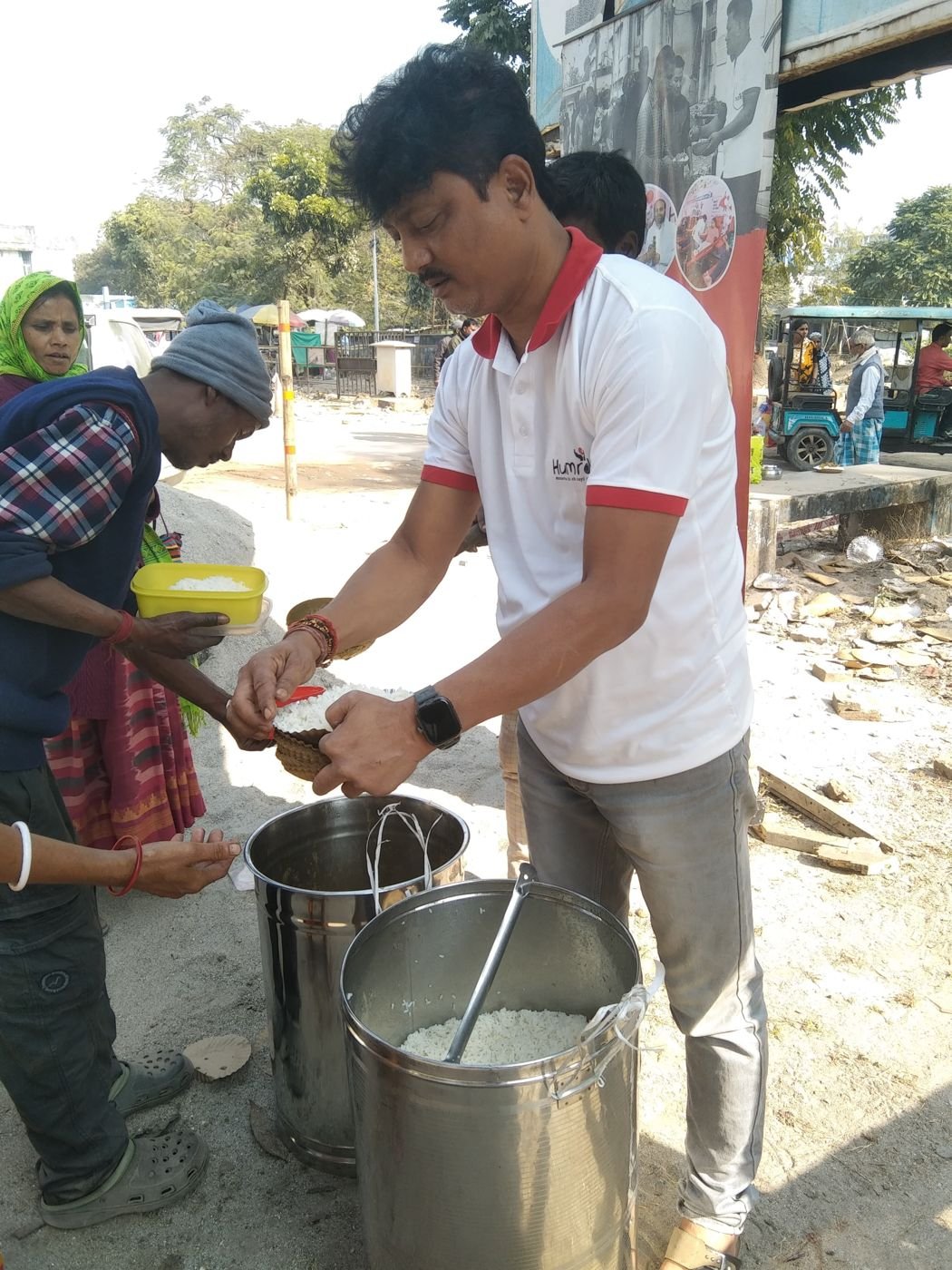 A volunteer serving hot food to people waiting in line in Siliguri