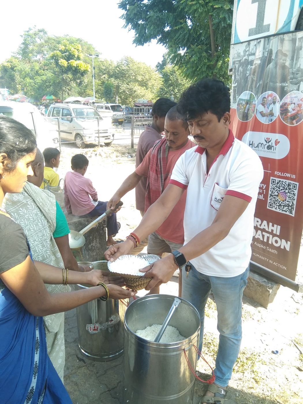 Volunteers filling plates from steel pots at a Humrahi food run