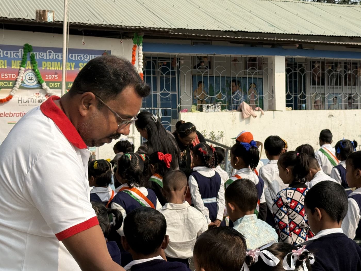 A Humrahi volunteer with schoolchildren holding tricolour flags at an adopted school near Siliguri