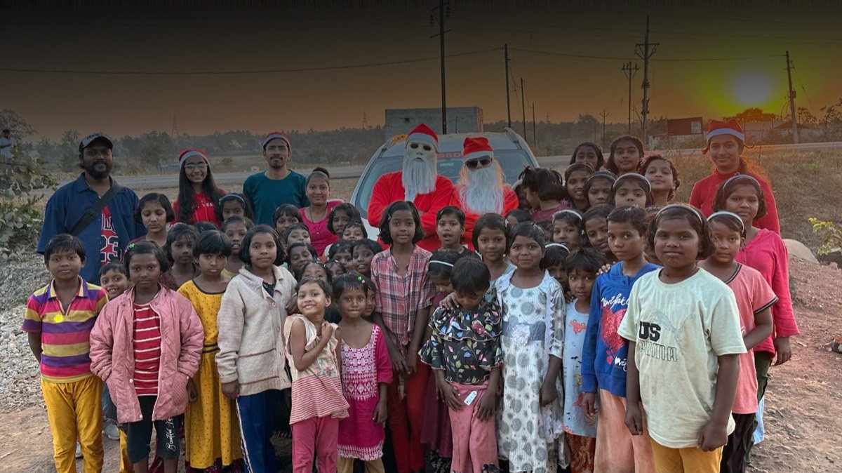 Support Wings volunteers in costume with a large group of children during a Little Smiles visit. This is not Siliguri and not a library.